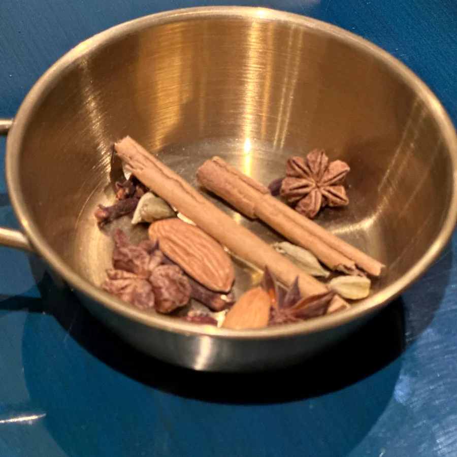 Cinnamon sticks, star anise, cardamom and almonds in a brass bowl
